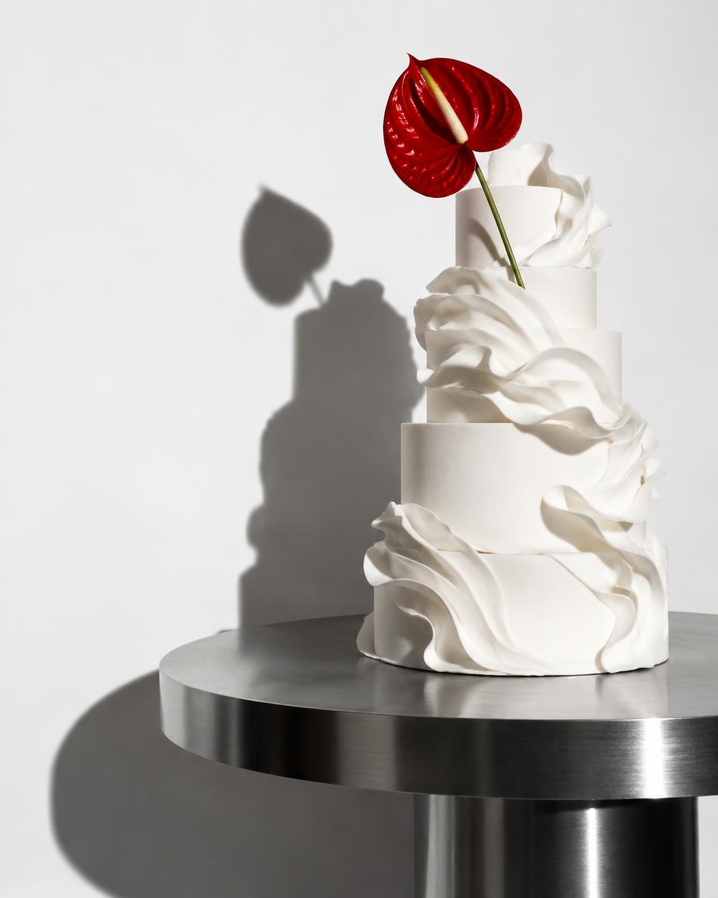 A sculptural white cake with a red anthurium